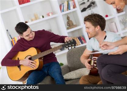 happy friends playing guitar and listening to music at home
