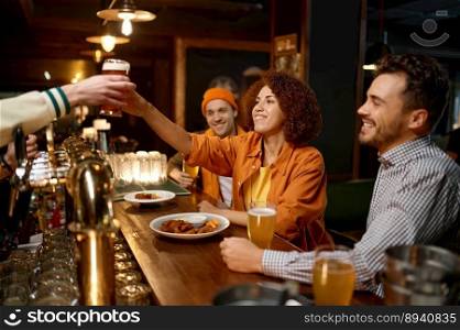 Happy friends rest in sports bar together. Focus on young pretty woman taking fresh glass of beer from bartenders hands. Cheerful millennial people sitting at counter desk drinking and eating snack. Happy friends company rest in sports bar together