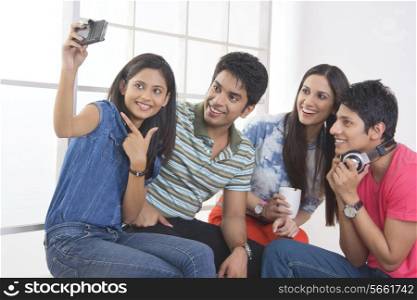 Happy friends taking self portrait through smart phone in college