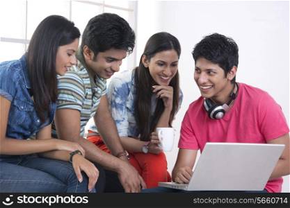 Happy friends using laptop in college