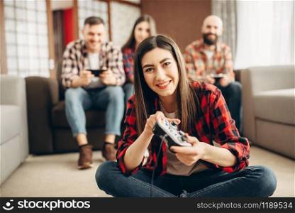 Happy friends with joysticks plays video console at home. Group of gamers playing videogame, male and female players have a competition