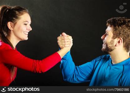 Happy friends young man and woman clasping shaking hands. Handshake greeting gesture in studio on black.
