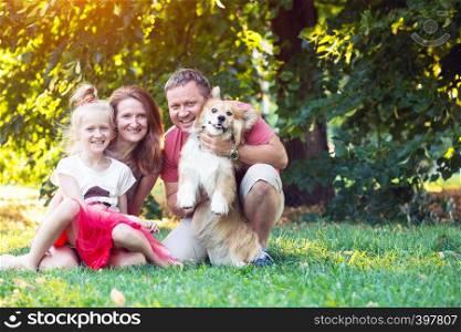 happy fun holidays - family and corgi fluffy on the lawn on a sunny summer day