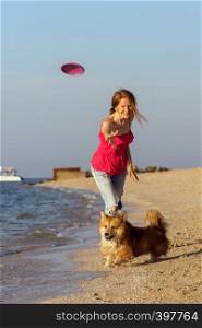 happy fun weekend by the sea - girl playing at the frisbee with a dog on the beach. Summer