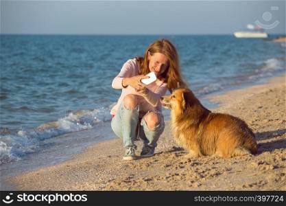 happy fun weekend by the sea - smiling girl with a dog do selfie on smartphone on the beach