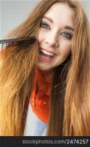 Happy funny teenage woman combing her long brown hair showing beautiful hairdo and non split ends.. Woman combing her brown hair