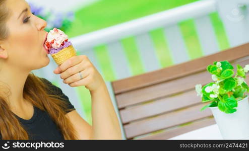 Happy funny young woman with long brown hair eating ice cream having fun.. Young woman eating ice cream