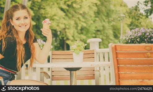 Happy funny young woman with long brown hair eating ice cream having fun.. Young woman eating ice cream