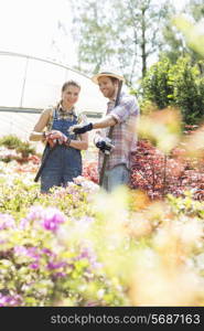 Happy gardeners discussing over plants outside greenhouse