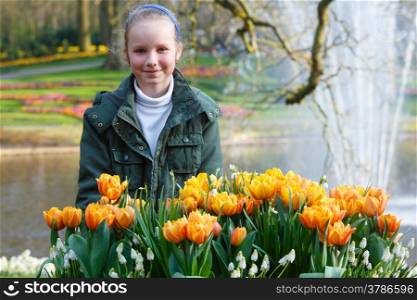 Happy girl and beautiful red-yellow tulips. Spring park.
