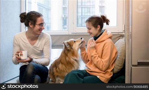 happy girl, boy and dog corgi sitting on the windowsill
