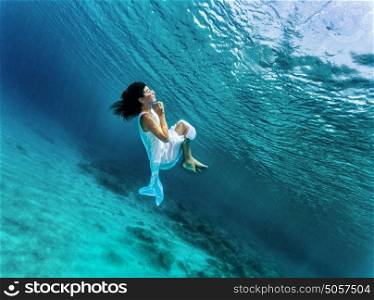 Happy girl dancing underwater, wearing stylish dress, luxury sea performance, active summer vacation, sport and art concept