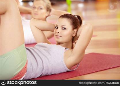 Happy girl does exercise for stomach muscles in sports club