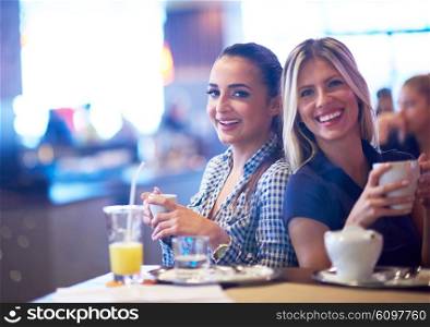 happy girl friends have cup of coffee in modern city restaurant