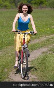 happy girl goes by bicycle on meadow
