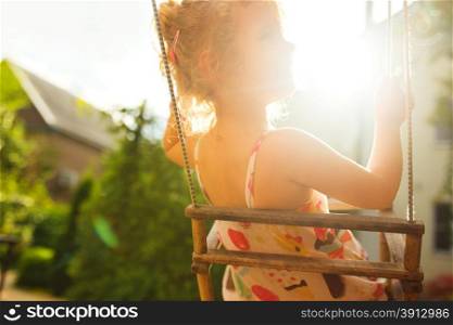 Happy girl having fun on a swing on summer day, lifestyle background, tinted photo