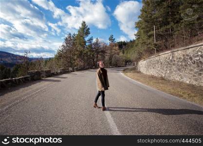 happy girl hipster stands on a mountain road of Romanian Carpathians mountains