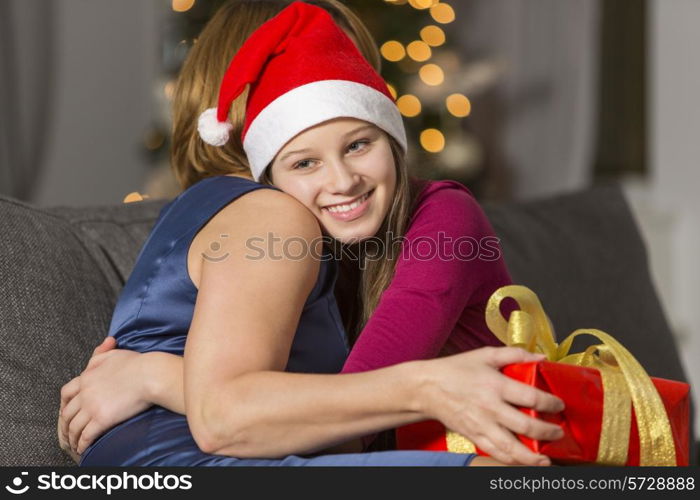 Happy girl hugging mother during Christmas at home