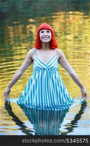 Happy girl in a lake with a blue drees looking up