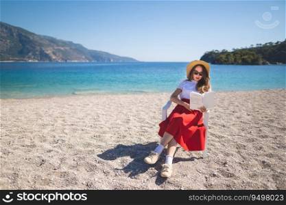 happy girl in a red skirt on an empty beach sits on a chair and reads a book