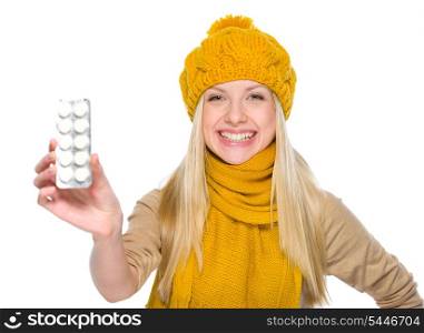 Happy girl in autumn clothes showing pills pack