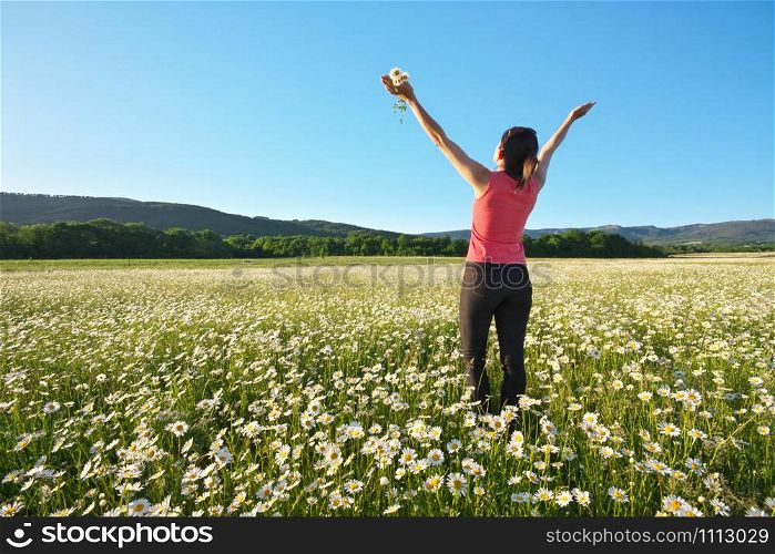 Happy girl in daisy wheel spring flower field. Emotional and nature scene.