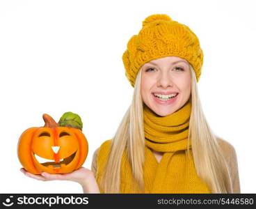 Happy girl in hat and scarf holding jack-o-lantern