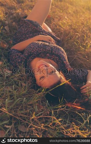 Happy girl in lying in tall grass in the fields