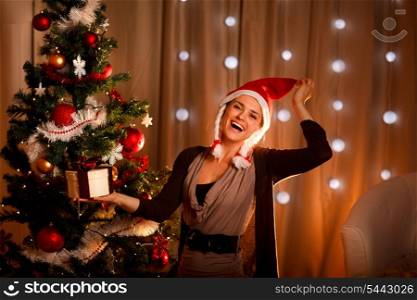 Happy girl in Santa hat near Christmas tree with present box&#xA;