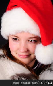 Happy girl in santa hat over black background