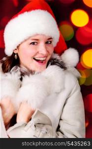 Happy girl in santa hat over blurred illuminated background
