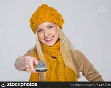 Happy girl in scarf and hat with tv remote control isolated on gray