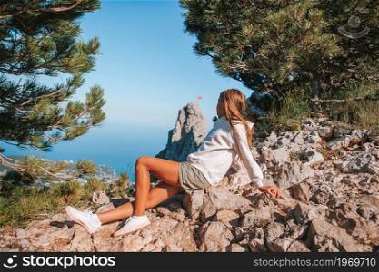 Happy girl in the mountains. Little kid on edge of cliff in mountains