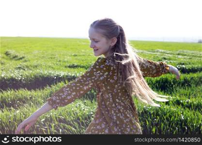 happy girl is joyful spinning in the green field. summer and freedom