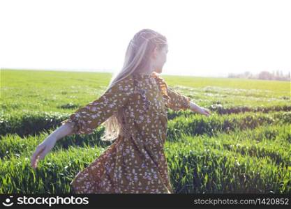 happy girl is joyful spinning in the green field. summer and freedom