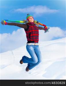 Happy girl jumping over blue sky and snow background, teen outdoor winter activities, female having fun at Christmastime, woman wearing colorful clothes, freedom and success concept