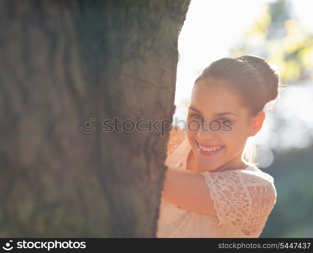 Happy girl looking out from tree