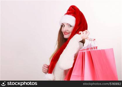 Happy girl on christmas shopping. Young cheerful woman with bags wearing santa cap. Holidays celebration commerce happiness leisure concept. . Happy girl on christmas shopping.