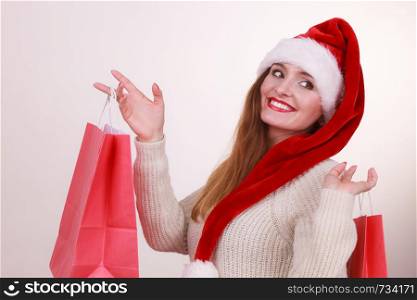 Happy girl on christmas shopping. Young cheerful woman with bags wearing santa cap. Holidays celebration commerce happiness leisure concept. . Happy girl on christmas shopping.