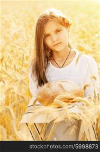 Happy girl on field of wheat with bread