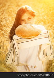 Happy girl on field of wheat with bread