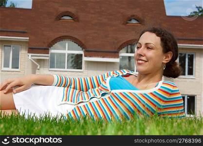Happy girl on lawn in front of new home. Smiling, she looks into distance. Horizontal format.