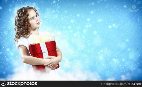 Happy girl opening gift box. A cute young girl holding a christmas gift, dark background with christmas light bokeh