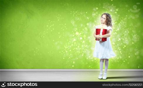 Happy girl opening gift box. A cute young girl holding a christmas gift, dark background with christmas light bokeh