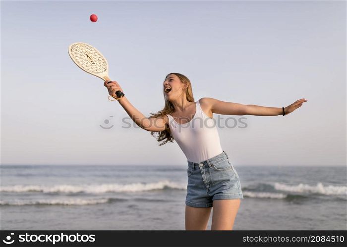 happy girl playing tennis near seashore