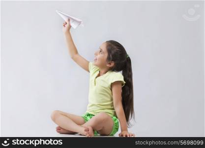 Happy girl playing with paper airplane isolated over gray background