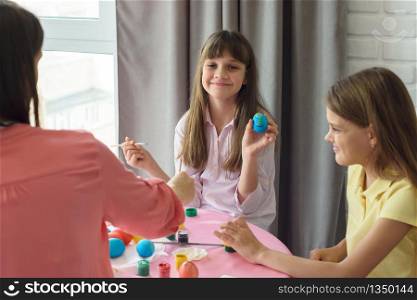 Happy girl shows a painted easter egg