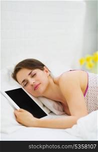 Happy girl sleeping embracing tablet PC