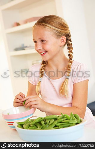 Happy girl splitting peas in kitchen