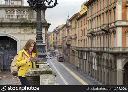 happy girl standing near parapet and looks at the map, Bologna. italy
